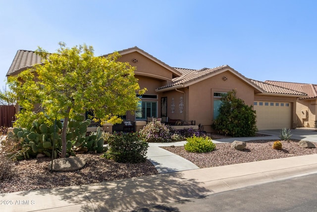 view of front facade featuring concrete driveway, an attached garage, a tile roof, and stucco siding