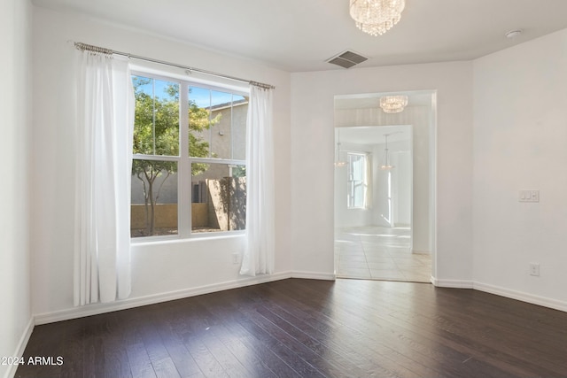 empty room with a chandelier and hardwood / wood-style flooring