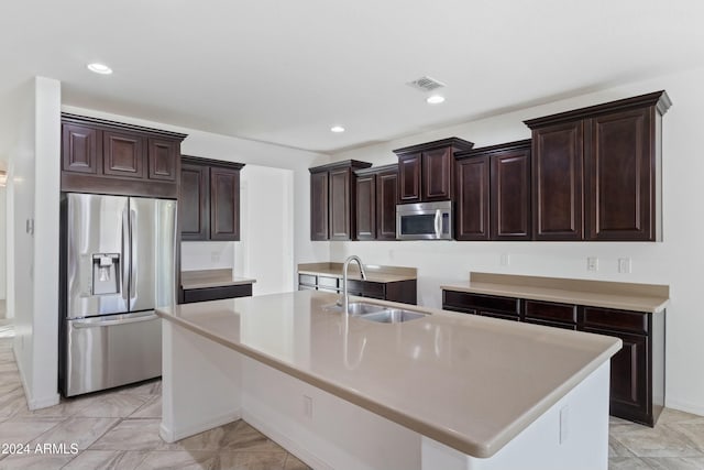 kitchen featuring dark brown cabinets, stainless steel appliances, a center island with sink, and sink