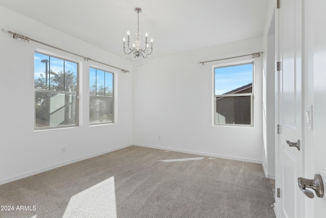 carpeted spare room featuring a notable chandelier and plenty of natural light