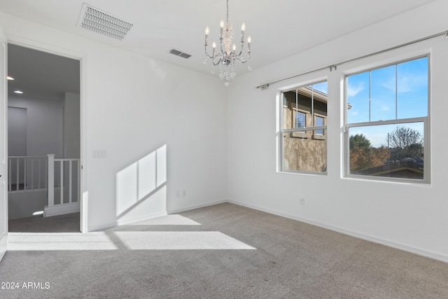 carpeted spare room with an inviting chandelier