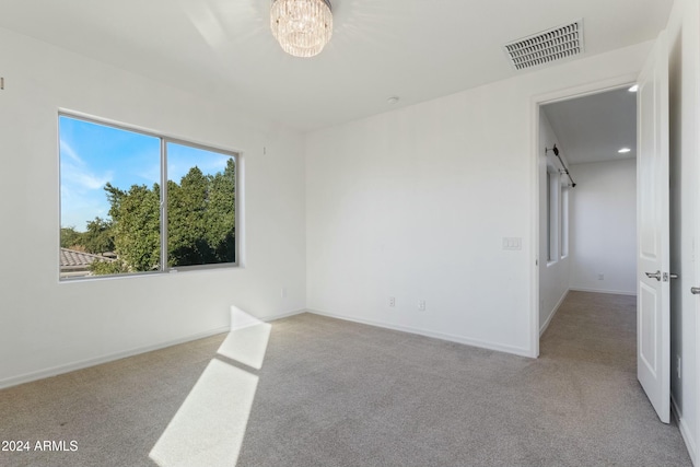 unfurnished room featuring a notable chandelier and light colored carpet