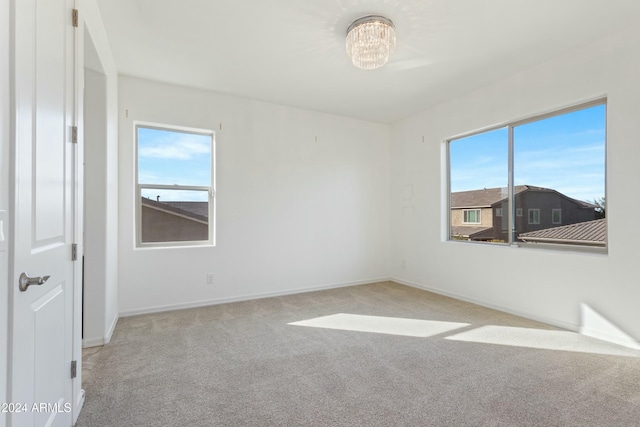 unfurnished room featuring light carpet and a chandelier