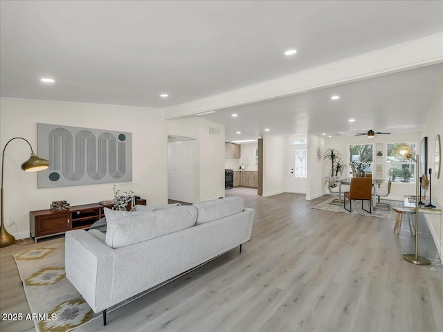 living room with recessed lighting, beam ceiling, and light wood finished floors