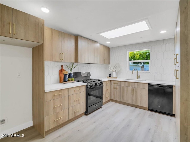 kitchen featuring light wood-style flooring, a sink, light countertops, black appliances, and tasteful backsplash