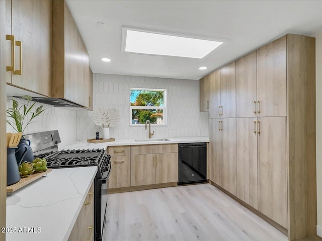 kitchen featuring a skylight, dishwasher, gas range, light brown cabinetry, and a sink