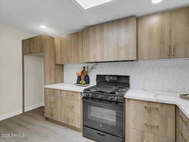 kitchen featuring light stone counters, backsplash, light wood-style floors, gas stove, and modern cabinets