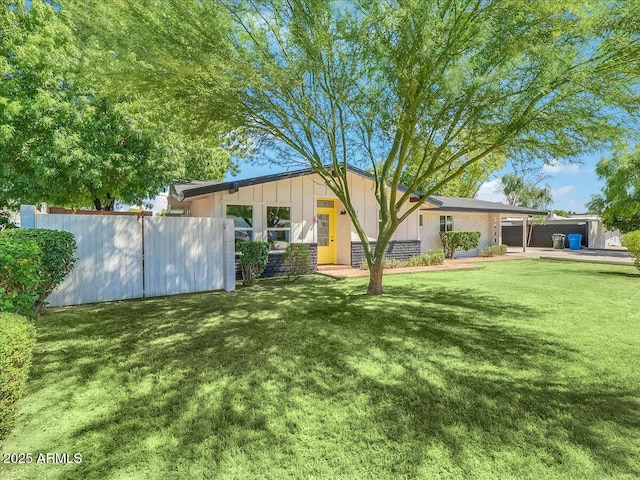 rear view of house with a yard, board and batten siding, and fence