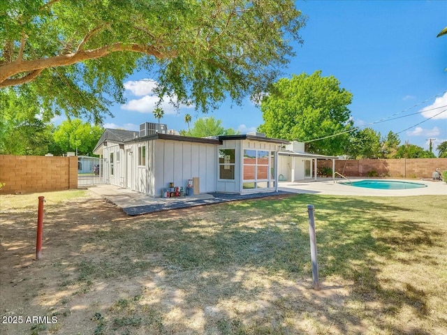 back of house featuring a fenced in pool, a lawn, a patio, a fenced backyard, and board and batten siding