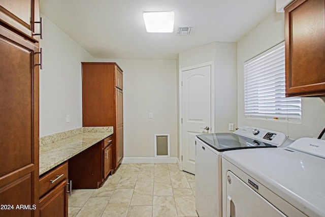 laundry room featuring light tile patterned floors, cabinets, and washer and clothes dryer