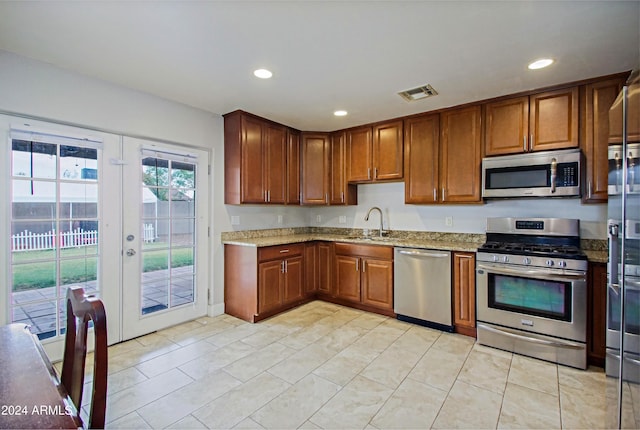 kitchen with light stone counters, light tile patterned flooring, sink, french doors, and stainless steel appliances