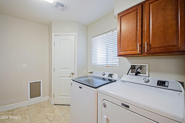 washroom with light tile patterned floors, washing machine and dryer, and cabinets