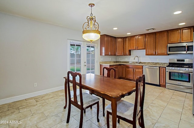 kitchen featuring appliances with stainless steel finishes, light stone countertops, sink, and hanging light fixtures