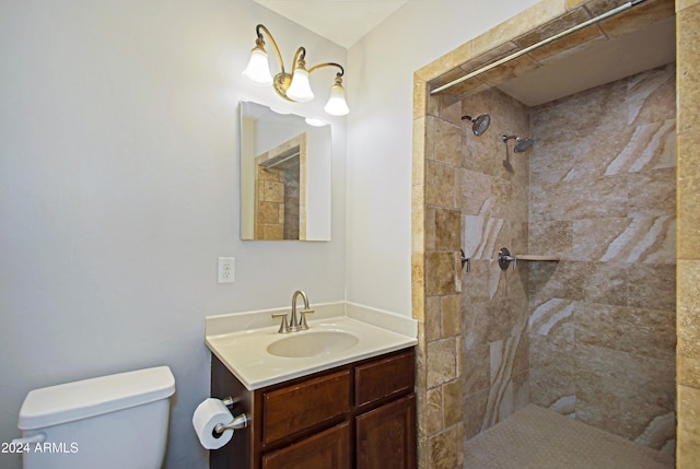 bathroom featuring a tile shower, toilet, and vanity