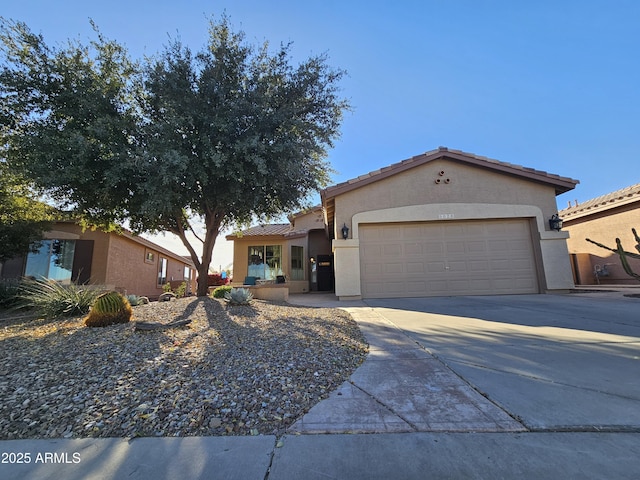 view of front of house featuring a garage, driveway, a tile roof, and stucco siding