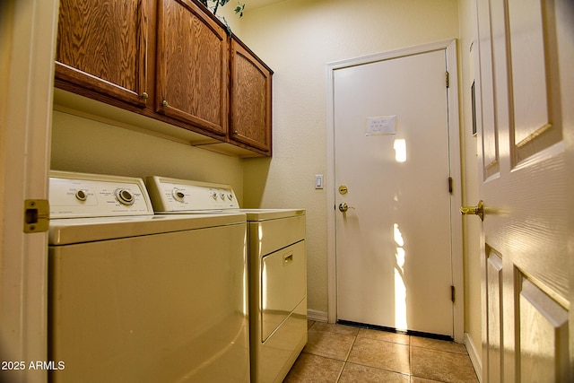 clothes washing area featuring cabinets, washing machine and clothes dryer, and light tile patterned floors