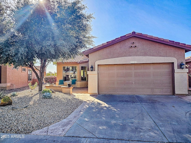 view of front facade featuring concrete driveway, a tiled roof, an attached garage, and stucco siding