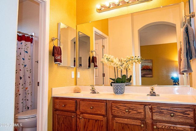 bathroom featuring double vanity, a shower with shower curtain, a sink, and toilet