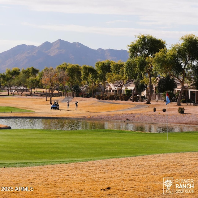 view of property's community featuring view of golf course, a lawn, and a water and mountain view