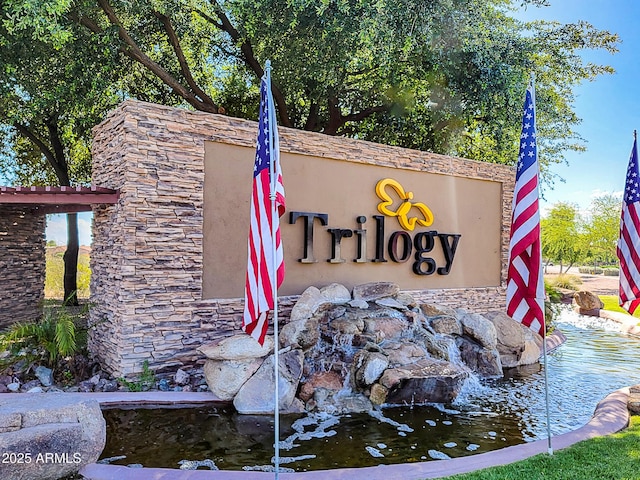 community / neighborhood sign featuring a small pond