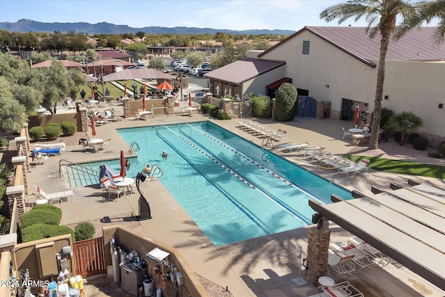 pool featuring a patio area, fence, and a mountain view