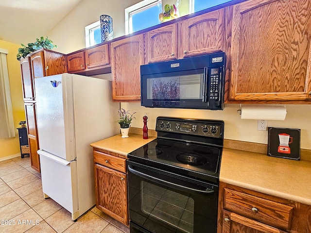 kitchen with light countertops, freestanding refrigerator, brown cabinetry, and black range with electric cooktop