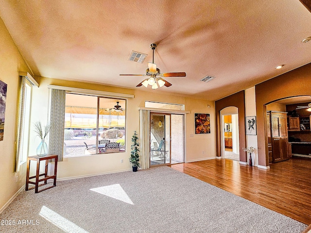 interior space with a ceiling fan, arched walkways, visible vents, and a textured ceiling