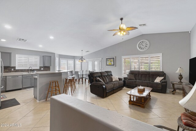 tiled living room featuring sink, ceiling fan, and vaulted ceiling