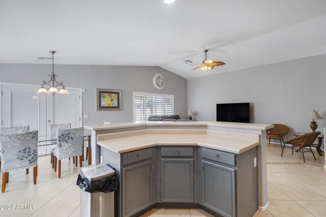 kitchen featuring vaulted ceiling, light tile patterned flooring, decorative light fixtures, gray cabinets, and ceiling fan with notable chandelier