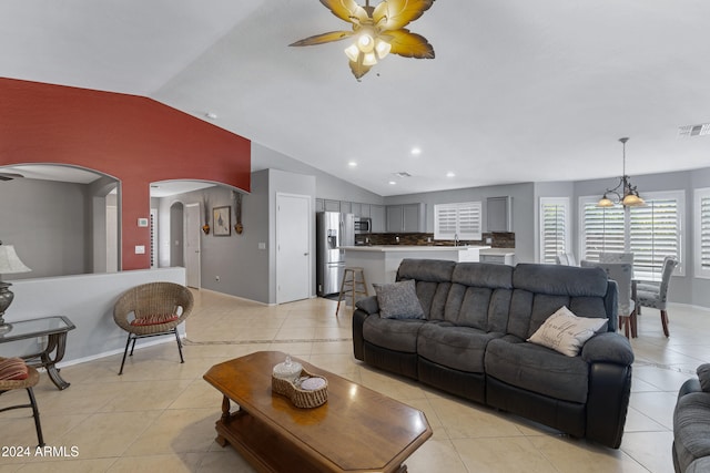 living room with light tile patterned flooring, vaulted ceiling, and ceiling fan with notable chandelier