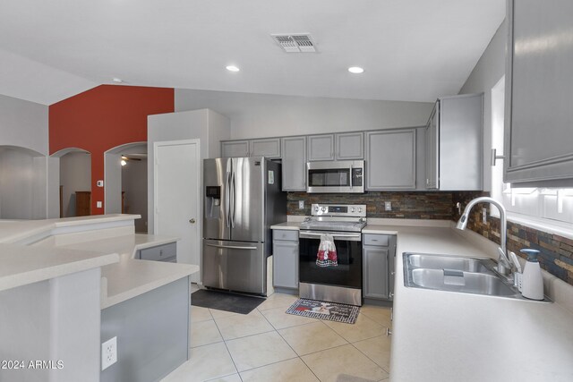 kitchen featuring lofted ceiling, stainless steel appliances, sink, and gray cabinetry