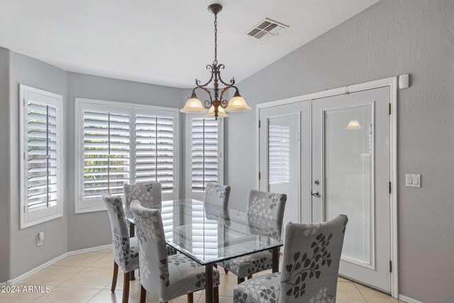 tiled dining area with a notable chandelier and lofted ceiling