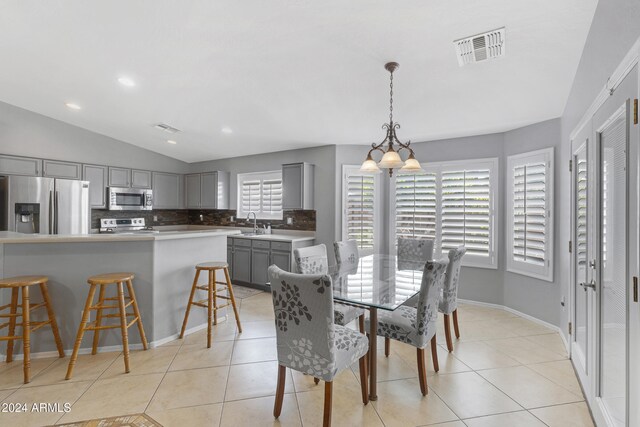 tiled dining room with lofted ceiling, sink, and a notable chandelier