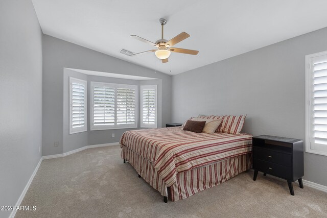 carpeted bedroom with multiple windows, vaulted ceiling, and ceiling fan