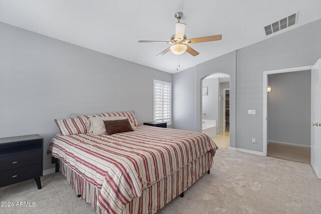 bedroom featuring ensuite bath, light carpet, and ceiling fan