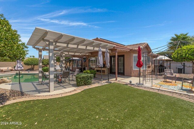 back of property with a lawn, a patio area, a fenced in pool, and a pergola