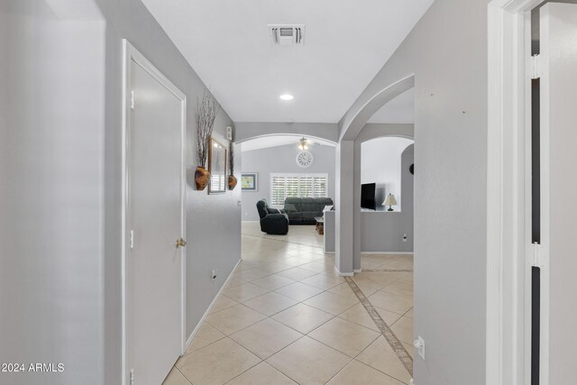 hallway featuring vaulted ceiling and light tile patterned floors