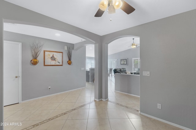 spare room featuring lofted ceiling, ceiling fan, and light tile patterned floors