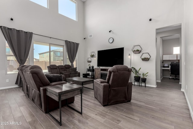 living area with light wood-style flooring, visible vents, and baseboards