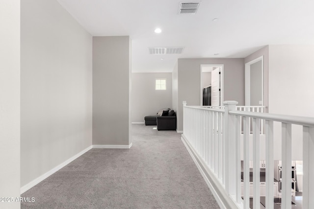 hall with visible vents, baseboards, and carpet