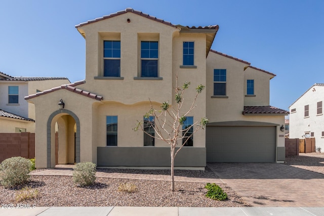 mediterranean / spanish home with stucco siding, a garage, and fence