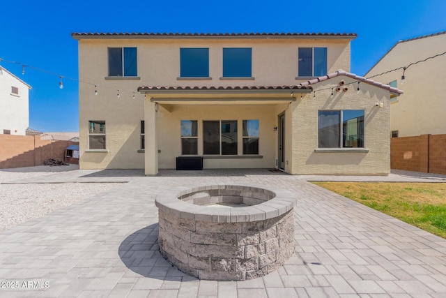 rear view of house featuring a patio area, stucco siding, an outdoor fire pit, and fence