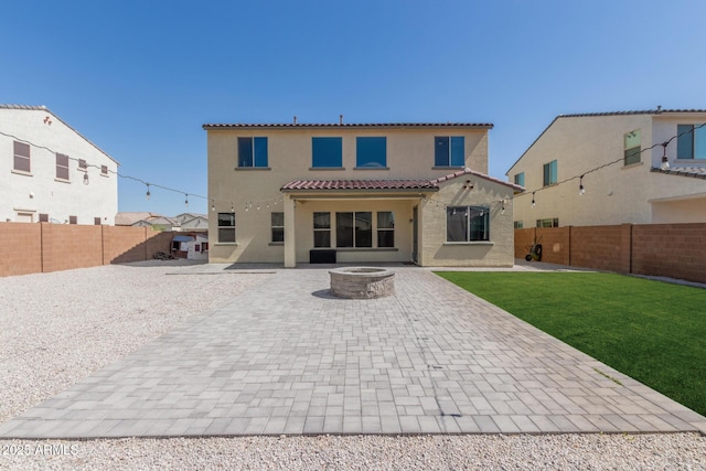 rear view of house featuring a tile roof, an outdoor fire pit, stucco siding, a fenced backyard, and a patio area