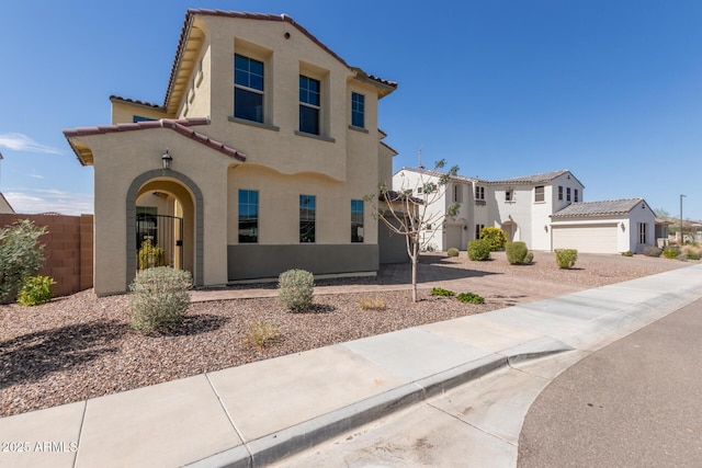 mediterranean / spanish home with fence, a residential view, a tiled roof, stucco siding, and a gate