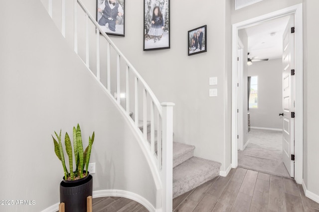 stairs featuring baseboards, ceiling fan, and wood finished floors