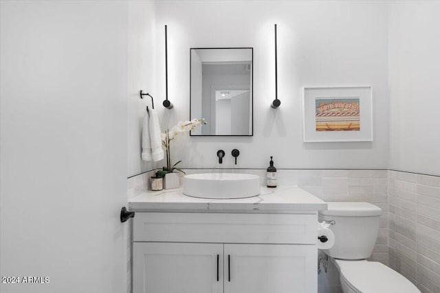 bathroom with tile walls, vanity, and toilet