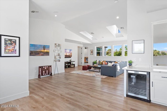 living room with a skylight, light hardwood / wood-style flooring, and beverage cooler