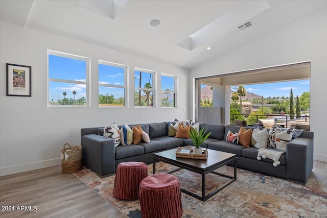 living room with light hardwood / wood-style flooring, vaulted ceiling, and a healthy amount of sunlight