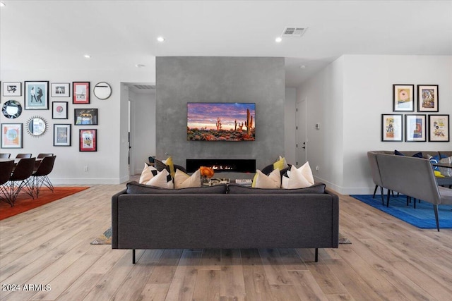 living room with a large fireplace and light hardwood / wood-style floors