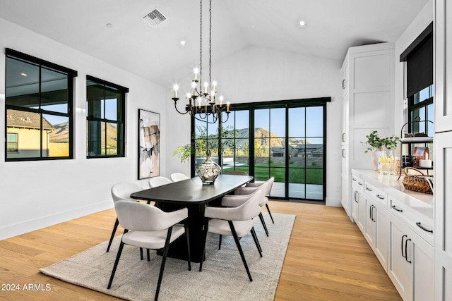 dining area featuring light hardwood / wood-style flooring, a chandelier, and high vaulted ceiling